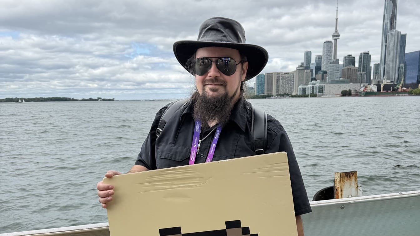 Metal (MetalXMeta) on the waterfront with his pixel board Metal (MetalXMeta) on a waterfront dock holding a pixel-art board, city skyline behind him